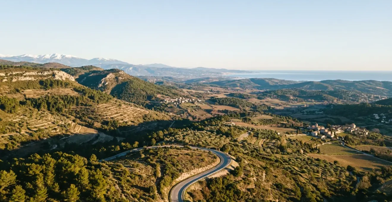 Vue aérienne d'une route sinueuse traversant des paysages français variés entre montagne et littoral