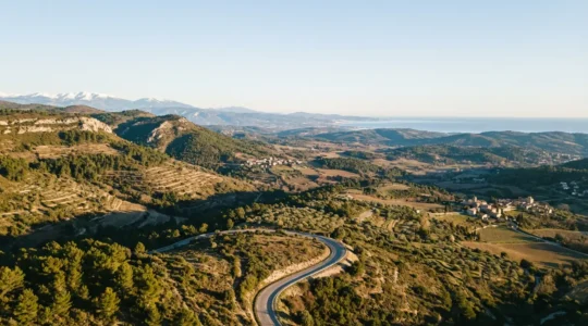 Vue aérienne d'une route sinueuse traversant des paysages français variés entre montagne et littoral