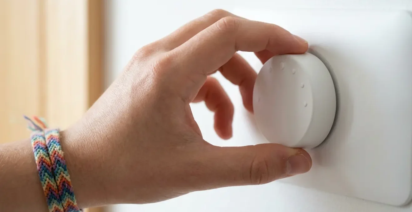 Main d'adolescent ajustant un thermostat mural moderne dans un intérieur de location