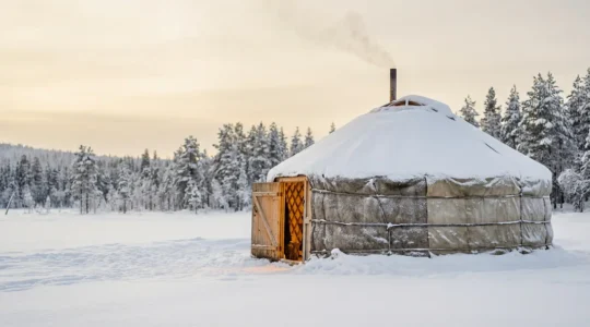 Yourte traditionnelle isolée sous la neige en hiver avec lumière chaleureuse émanant de l'intérieur